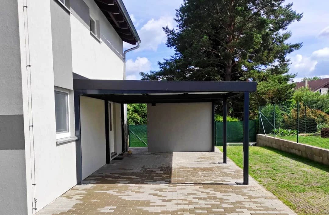 Montovaný prístrešok pri dome so šikmou strechou